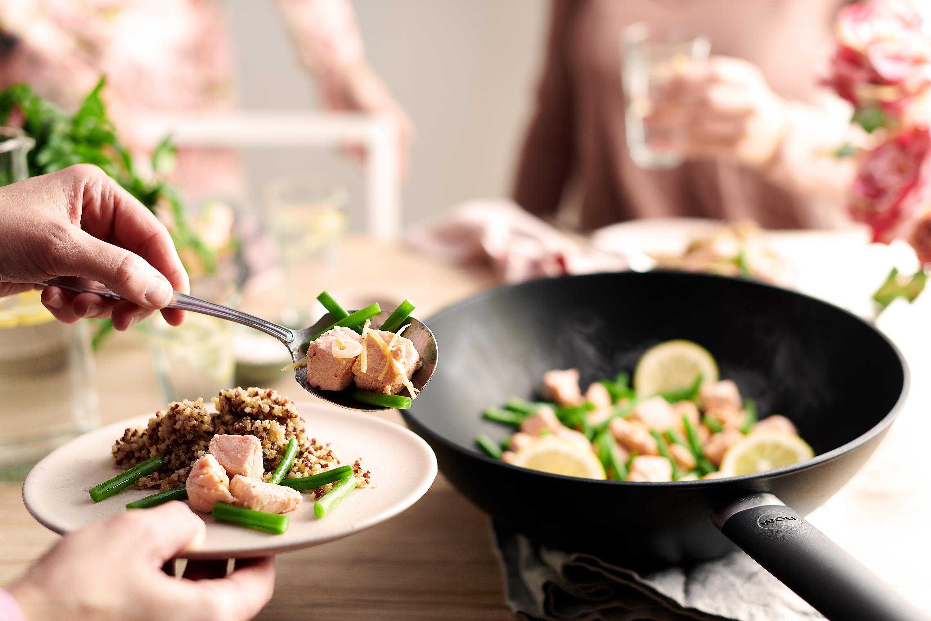 In einer Eco Lite QXR Wok- und Rührpfanne wird Lachs mit grünen Bohnen zubereitet und auf einem Teller platziert. 